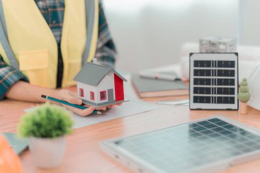 İki mühendis rüzgar türbini model bileşenleri üzerinde çalışıyor ve çözümün yenilenebilir enerji kaynaklarını bilgisayarla tartışıyor. Sürdürülebilir enerji projeleri geliştirmek için rüzgar türbini güneş paneli modeli.