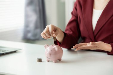 Kadının eli tasarruf etmek için pembe kumbaraya bozuk para atıyor. Tasarruf ve mali planlama kavramı. İş yatırımı. Kapat..