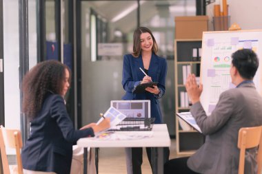 Takım çalışmasının sonuçlarını gösteren çizelge ve grafikleri tartışan bir grup iş stratejisi hakkında modern ofiste finansal verileri analiz eden bir grup iş adamı..
