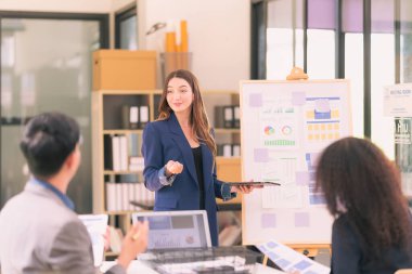 Takım çalışmasının sonuçlarını gösteren çizelge ve grafikleri tartışan bir grup iş stratejisi hakkında modern ofiste finansal verileri analiz eden bir grup iş adamı..