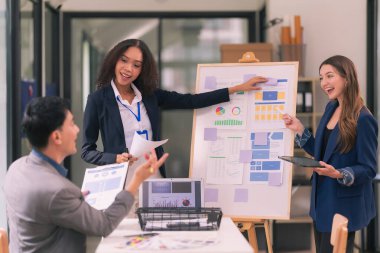 Takım çalışmasının sonuçlarını gösteren çizelge ve grafikleri tartışan bir grup iş stratejisi hakkında modern ofiste finansal verileri analiz eden bir grup iş adamı..