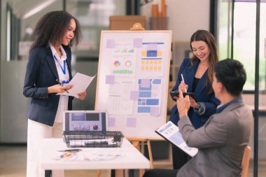 Takım çalışmasının sonuçlarını gösteren çizelge ve grafikleri tartışan bir grup iş stratejisi hakkında modern ofiste finansal verileri analiz eden bir grup iş adamı..