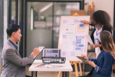 Takım çalışmasının sonuçlarını gösteren çizelge ve grafikleri tartışan bir grup iş stratejisi hakkında modern ofiste finansal verileri analiz eden bir grup iş adamı..