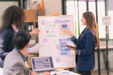 Takım çalışmasının sonuçlarını gösteren çizelge ve grafikleri tartışan bir grup iş stratejisi hakkında modern ofiste finansal verileri analiz eden bir grup iş adamı..