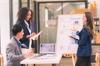 Takım çalışmasının sonuçlarını gösteren çizelge ve grafikleri tartışan bir grup iş stratejisi hakkında modern ofiste finansal verileri analiz eden bir grup iş adamı..