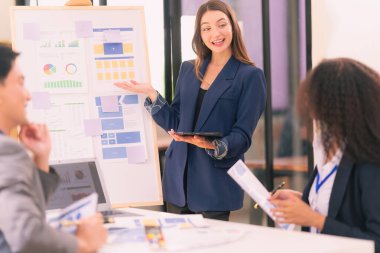 Takım çalışmasının sonuçlarını gösteren çizelge ve grafikleri tartışan bir grup iş stratejisi hakkında modern ofiste finansal verileri analiz eden bir grup iş adamı..