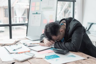 Yorgun bir ofis çalışanı dizüstü bilgisayarla masada uyuyor. Sabah ofiste enerji eksikliği var. Stres yorgunluğu. İş yerinde uyku sorunları.