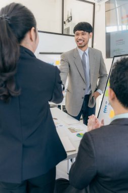 İş ekibi ofisinde ve sözleşme imzaladıktan sonra el sıkışıyorlar. İş arkadaşları ofiste dizüstü bilgisayar ve veri tablosuyla el ele tutuşuyorlar.