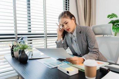 Asyalı işkadını, elinde buruşmuş kağıt tutarken, ofiste mali belgeler ve dizüstü bilgisayarla çalışırken, bunun altını çizdi. İşle ilgili sorunlarım var, hayal kırıklığına uğradım..