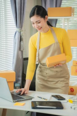Asyalı kadın teslimat konsepti, serbest çalışma, çevrimiçi alışveriş, dizüstü bilgisayarda çalışma evde paket kutusu, internet üzerinden KME işi, dikey fotoğraf.