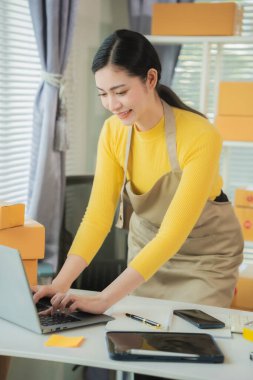 Asyalı kadın teslimat konsepti, serbest çalışma, çevrimiçi alışveriş, dizüstü bilgisayarda çalışma evde paket kutusu, internet üzerinden KME işi, dikey fotoğraf.