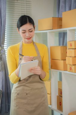 Asyalı kadın teslimat konsepti, serbest çalışma, çevrimiçi alışveriş, dizüstü bilgisayarda çalışma evde paket kutusu, internet üzerinden KME işi, dikey fotoğraf.