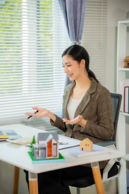 Asyalı kadın emlakçı yeni ev alımı için iş sözleşmelerini, kira sözleşmelerini, kredileri ve bankaları anlatıyor.