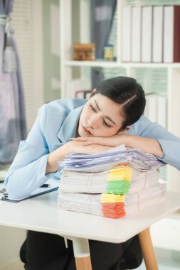 Masasında belgeler ve dosyalarla çalışan bir kadın var. Belgeleri düzenlemek, mali bilgileri gözden geçirmek. Masasında bir yığın belge tutarken önemli belgeleri inceliyor..