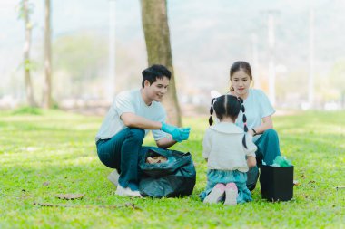 Yaz tatilinde Asyalı aile, çocuklara plastik şişe ve çöp toplamayı öğreten ebeveynler, çevreyi korumak için gönüllü konsept..