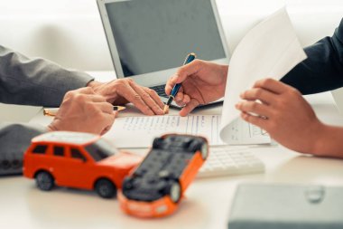 Sigorta acentesinin eli masadaki kırmızı oyuncak arabayı koruyor. Ulaşım finansmanını yönetmeyi planlıyorum. Araba sigortası konsepti.