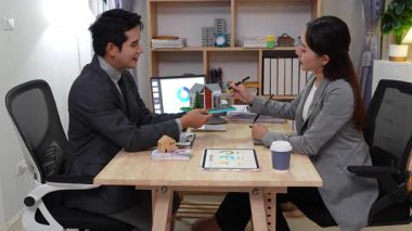 Genç Asyalı çift emlakçıyla detaylı bir görüşme yapıyor. Çevre dostu ev hakkında emlakçıya danışmak.