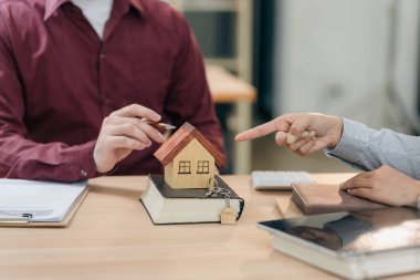 Emlakçı, yeni alıcıyı müşterilerine model ev sunarak tebrik ediyor. Ofisteki müşteriyle yakın plan bir emlakçı görüşmesi..