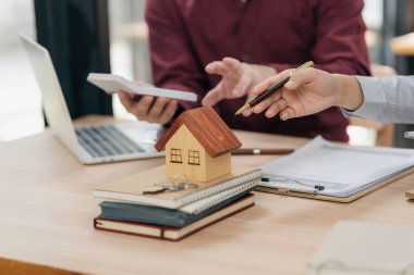 Emlakçı, yeni alıcıyı müşterilerine model ev sunarak tebrik ediyor. Ofisteki müşteriyle yakın plan bir emlakçı görüşmesi..