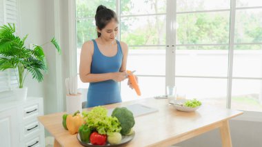 Mutlu Asyalı kadın ev egzersizinden sonra bir kase taze salatanın tadını çıkarıyor. Modern bir mutfakta besleyici bir yemeğin tadını çıkarıyorum..