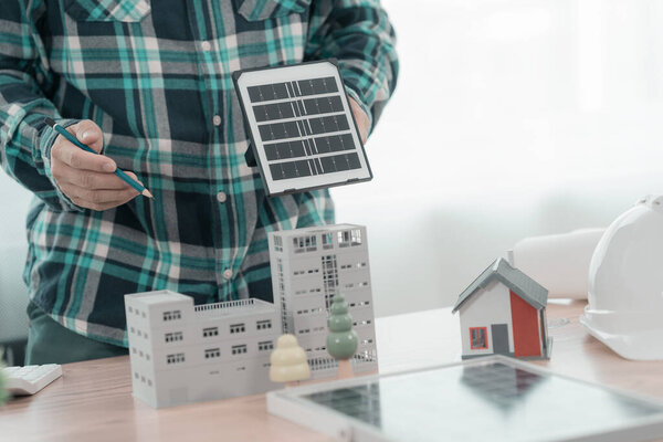Инженер или архитектор, работающий над чертежами солнечных панелей в офисе. Концепция строительства.