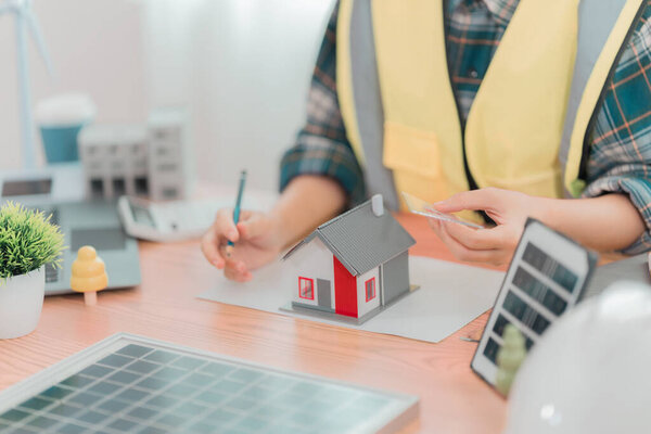 Инженер или архитектор, работающий над чертежами солнечных панелей в офисе. Концепция строительства.