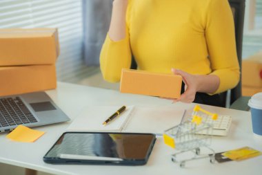 KOBİ tedarik zinciri kavramı, satın alma, Asyalı kadın girişimci dizüstü bilgisayar üzerinde çalışırken not alıyor, müşteri küçük işletme mağazalarında siparişleri yönetiyor.