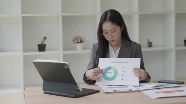 Asyalı iş kadını, konferans odasında boş beyaz tablet üzerinde bilgisayar kullanarak, konuşarak, tartışarak ve iş problemlerini çözerek belgeyi açıklıyor.