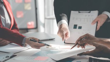 İş adamları başarılı takım çalışmalarının sonuçlarını, borsa grafiklerini ve ofisteki tabletleri işaret eden grafikleri tartışıyor..