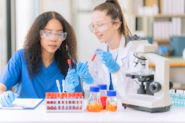 Bilim konsepti. İki kadın doktor modern bir tıp laboratuarında mikroskop altında maddeler üzerinde araştırma yapıyorlar..