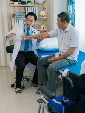 Yetenekli bir erkek fizyoterapist yaşlı bir erkek hastayı muayene ediyor. Yatakta yatıyor. Hastane muayene odasında kas gücünü kontrol ediyor..