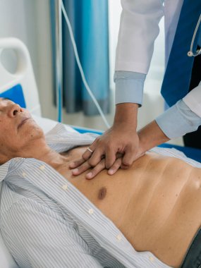 Kalp krizi geçiren biri için kalp masajı ya da ilk yardım uygulamak. Tıbbi bir tesiste kalp krizi geçiren tepkisiz bir erkek hasta için kalp masajı..