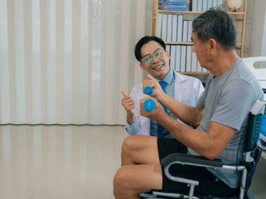 Asyalı fizyoterapist ve tekerlekli sandalyedeki yaşlı hasta halter kemeri tutuyor. Dambılı sağlık hizmeti. Yaşlı insanlar yaşlanıyor. Uyumlu spor aktiviteleri.