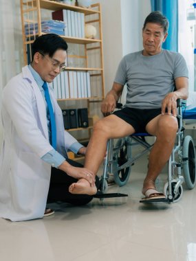 Yetenekli bir erkek fizyoterapist yaşlı bir erkek hastayı muayene ediyor. Yatakta yatıyor. Hastane muayene odasında kas gücünü kontrol ediyor..