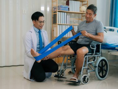 Kıdemli Asyalı adam ayak kaslarını esnetmek için direnç bandı kullanıyor. Evde bakıcı ile egzersiz yapma fizyoterapi konsepti.