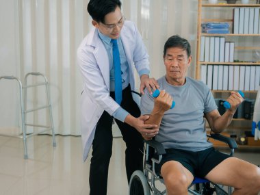 Asyalı fizyoterapist ve tekerlekli sandalyedeki yaşlı hasta halter kemeri tutuyor. Dambılı sağlık hizmeti. Yaşlı insanlar yaşlanıyor. Uyumlu spor aktiviteleri.