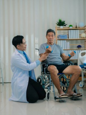 Asyalı fizyoterapist ve tekerlekli sandalyedeki yaşlı hasta halter kemeri tutuyor. Dambılı sağlık hizmeti. Yaşlı insanlar yaşlanıyor. Uyumlu spor aktiviteleri.