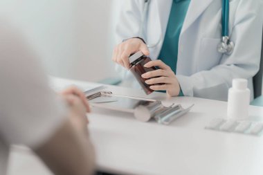 Doktor ve hasta masada otururken çeşitli konuları tartışıyorlar. Tıp ve sağlık hizmetleri kavramı. Doktor hasta için bilgi içeren panoyu gösterir.