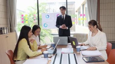 İş ortakları bir toplantıda belge ve fikirleri tartışıyor ve iş adamları ve kadınlar birlikte çalışırken mutlu bir şekilde gülümsüyorlar. 4k ağır çekim videosu.