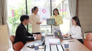 İş ortakları bir toplantıda belge ve fikirleri tartışıyor ve iş adamları ve kadınlar birlikte çalışırken mutlu bir şekilde gülümsüyorlar. 4k ağır çekim videosu.