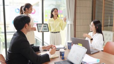 İş ortakları bir toplantıda belge ve fikirleri tartışıyor ve iş adamları ve kadınlar birlikte çalışırken mutlu bir şekilde gülümsüyorlar. 4k ağır çekim videosu.