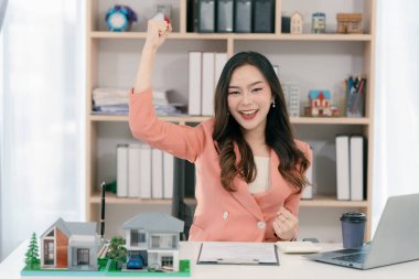 Heyecanlı Asyalı genç emlakçı evini yatırım için satıyor ve iş ve finans sunumları sunuyor..