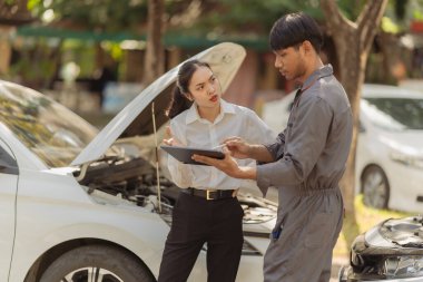 Asian man and woman sitting on the road with car insurance claim form. Car accident compensation. Transportation concept. Traffic accident and insurance.