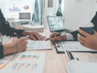 Meeting and discussion of charts and graphs showing the results of successful teamwork, stock market graphs and pointing fingers on tablets in the office.