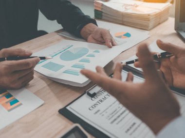 Meeting and discussion of charts and graphs showing the results of successful teamwork, stock market graphs and pointing fingers on tablets in the office.