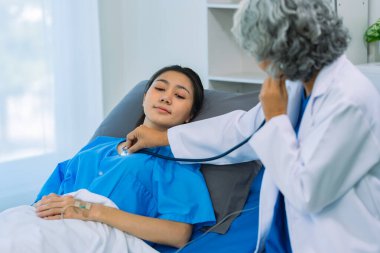 Senior female doctor holding stethoscope examining female patient checking heart rate, heart disease healthcare concept, female patient, proper care