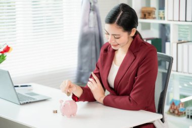Financial planning and investment concept. Young Asian woman is putting coins into a piggy bank. Investment concept. Saving money. Investing.