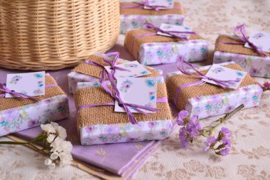 Düğün leylak rengi, mor el yapımı sabunları doğal kahverengi çuval bezi kumaşlarıyla süslüyor. Şık, sade parti resepsiyonu için orijinal konuk hediyeleri, diy hediye kutuları.