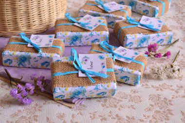 İlk komünyon doğum günü hediyeleri. Çiçek kağıdına sarılı orijinal hediyeler. Kahverengi çuval bezi süslemeli, kurdeleli ve kız isimli koztom etiketli.