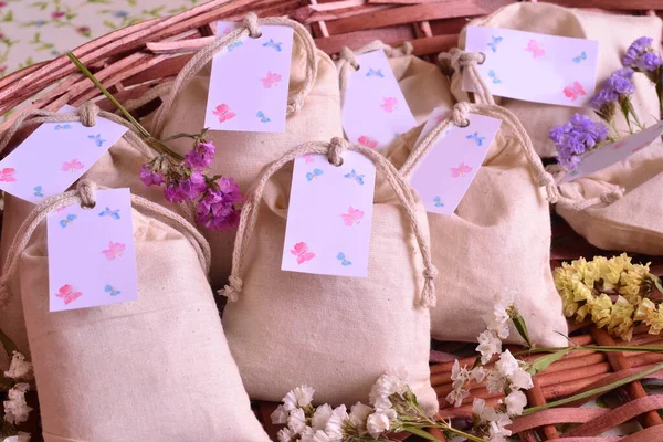 Wedding favours cotton bags scented sachets, small guest gifts, original event presents personalized with custom label decoration, brown wicker and flowers background, business sell online handmade